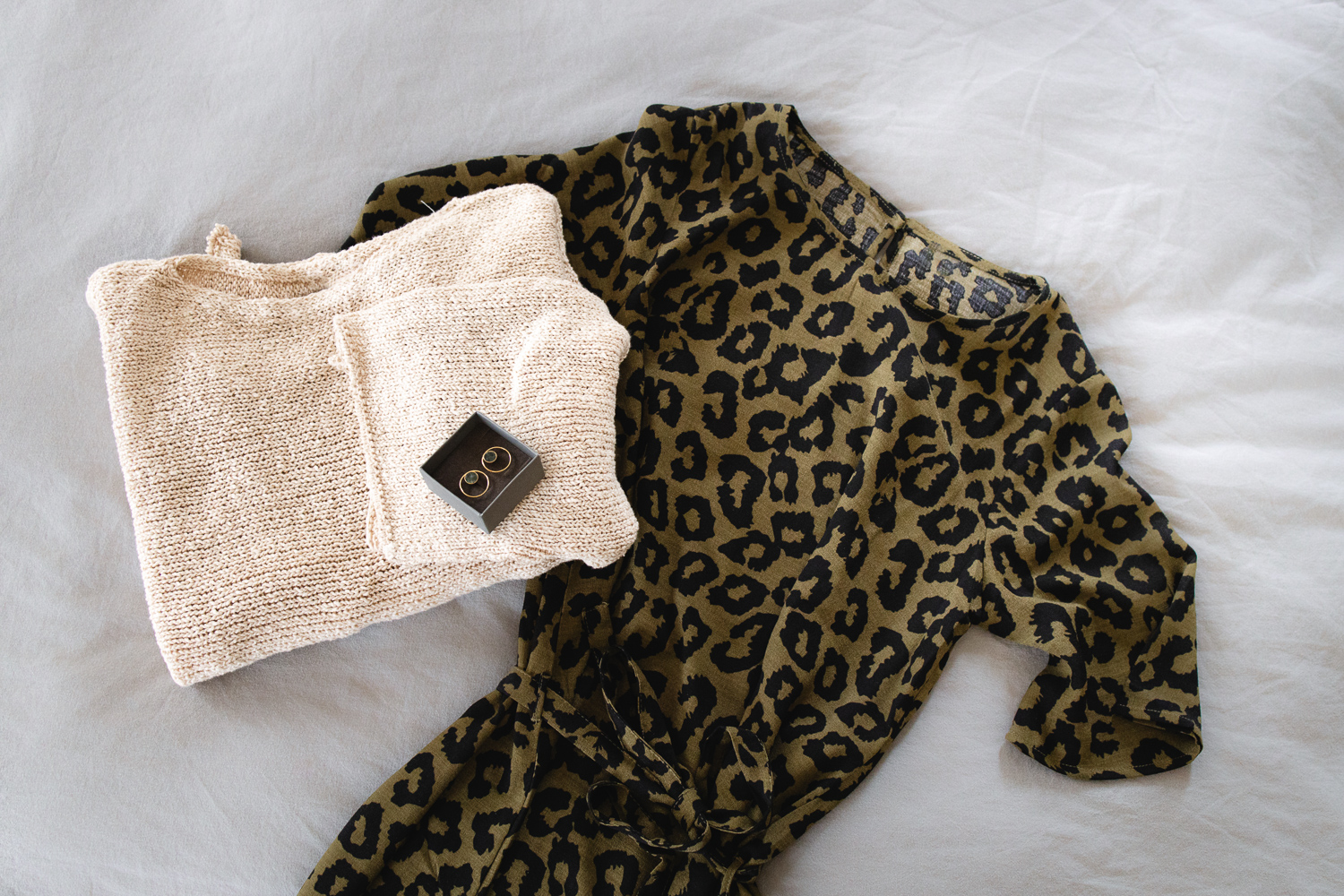 Ein Kleid und ein Pullover auf dem Bett ausgelegt